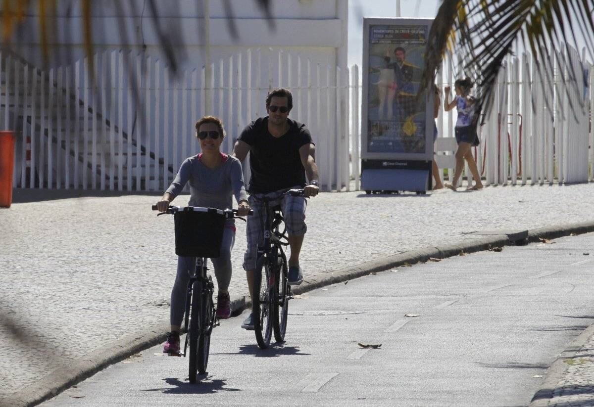 Adriana Esteves e Vladimir Britcha andam de bicicleta na praia da Barra, no Rio