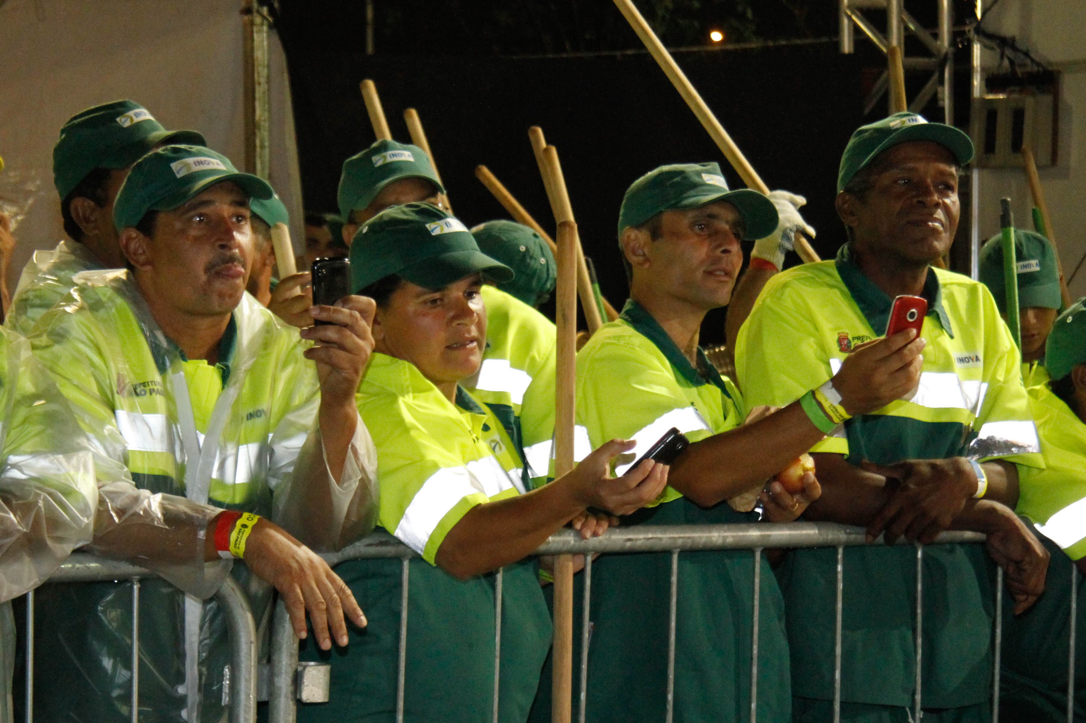Munidos de câmeras fotográficas, garis assistem aos desfiles desfiles de local privilegiado