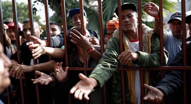 Imigrantes aguardam para receber comida em abrigo de Tijuana, no México