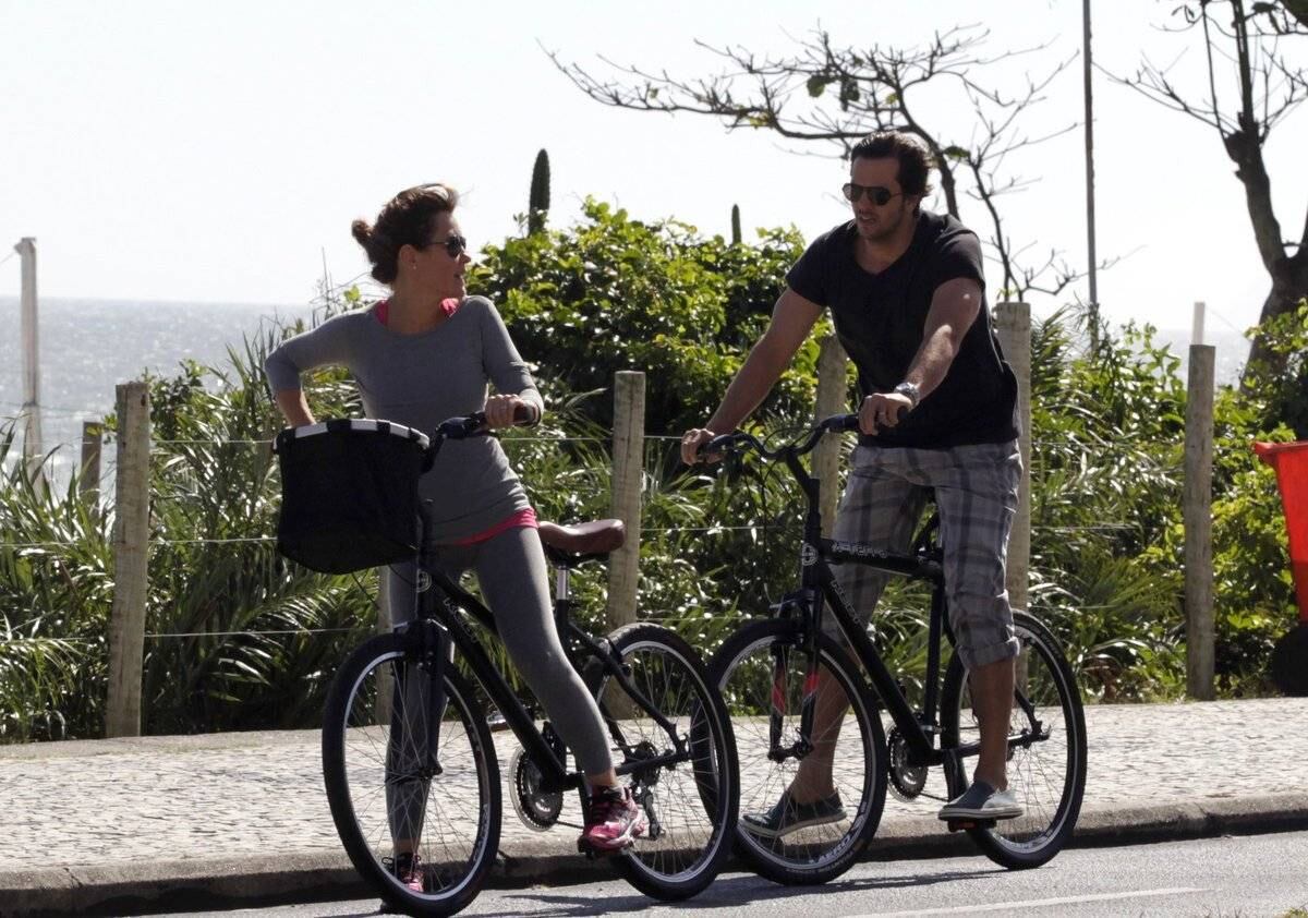 Adriana Esteves e Vladimir Britcha andam de bicicleta na praia da Barra, no Rio