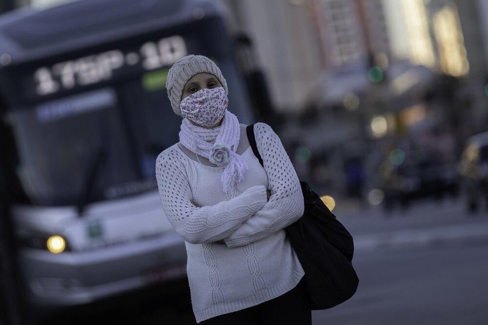 Mulher agasalhada usando máscara de proteção