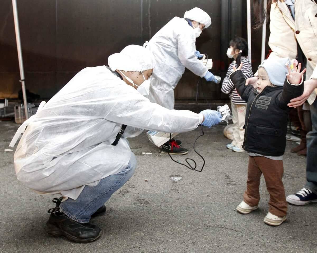 Funcionários
devidamente protegidos checam sinais de radiação em uma criança que foi
obrigada a deixar a área próxima à usina de Fukushima