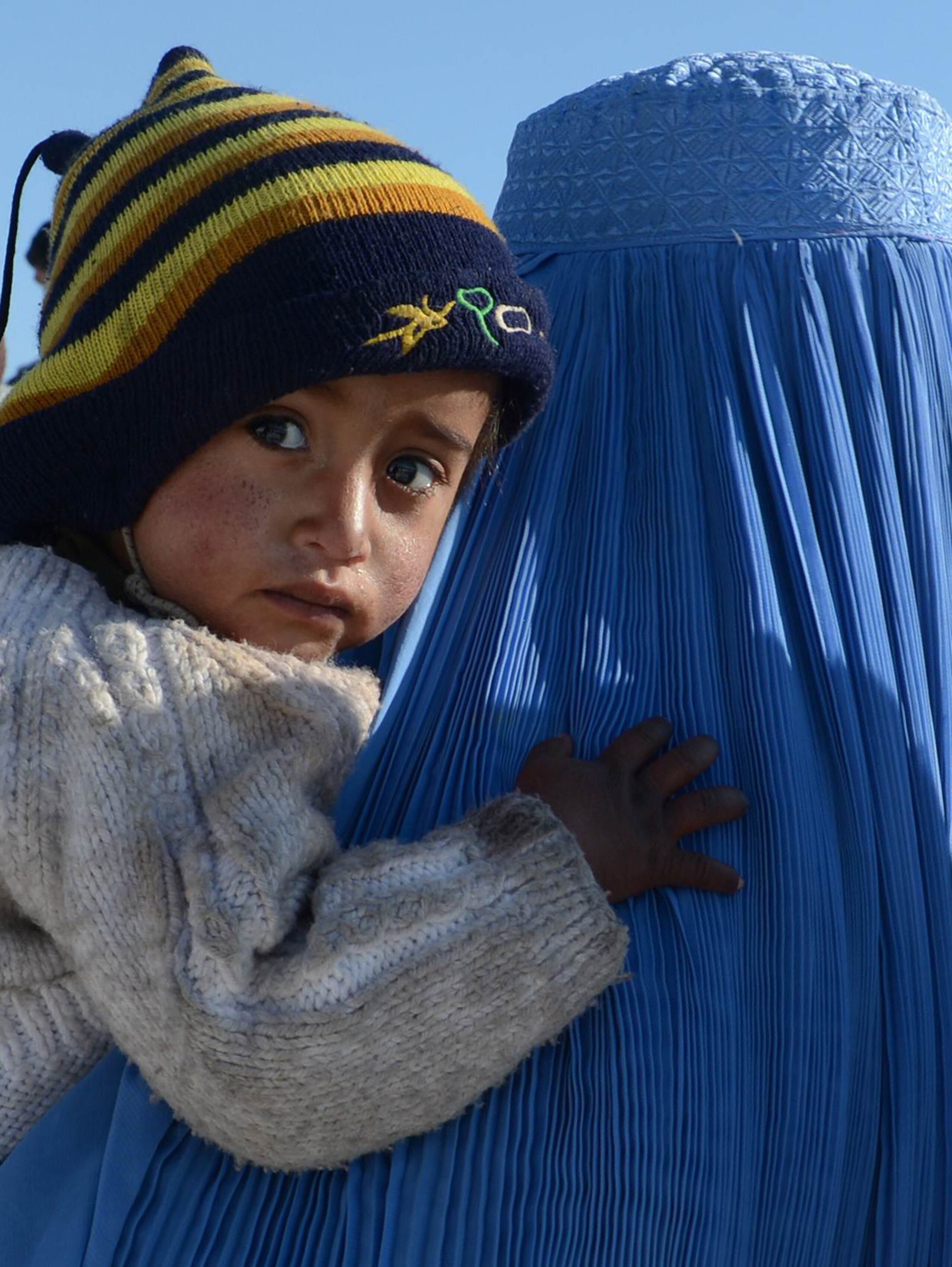 Afegã segura o filho enquanto espera em fila para receber suprimentos de inverno em Cabul, Afeganistão. Cerca de um terço dos afegãos vive abaixo da linha da pobreza