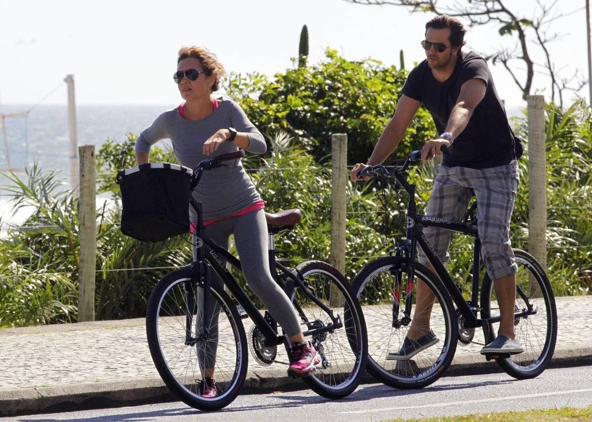 Adriana Esteves e Vladimir Britcha andam de bicicleta na praia da Barra, no Rio