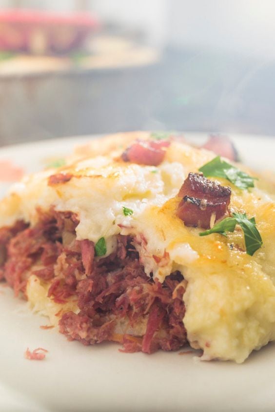 Prato principal: Escondidinho de carne seca com manteiga de garrafa

Ingredientes

Para o purê de mandioca
• 500g de mandioca cozida e amassada
• 2 xícaras da água do cozimento da mandioca com 4 colheres de leite em pó (ou 2 xícaras de leite comum)
• 1/2 cebola picada
• 1 dente de alho picado
• Manteiga de garrafa a gosto
• Sal e pimenta do reino a gosto

Para o refogado de carne seca
• 500g de carne seca dessalgada e desfiada
• 1/2 cebola picada
• 1 dente de alho picado
• 3 colheres de sopa de tomatinhos confitados (ou 1 tomate picadinho)
• 10 pimentas biquinho cortadas em 4
• Cheiro-verde a gosto
• Manteiga de garrafa a gosto

Modo de preparo

Numa panela, coloque manteiga de garrafa e refogue a cebola e o alho até ficarem transparentes; adicione a carne seca já desfiada, os tomates confitados e misture bem. Adicione o cheiro-verde e desligue o fogo; por último adicione as pimentas biquinho e reserve; em outra panela, também refogue a cebola e o alho na manteiga de garrafa, adicione a mandioca já amassada, adicione a água do cozimento da mandioca já misturada com o leite em pó (ou somente o leite comum), misture bem para agregar. Mexa bem, vai virar um purê bem denso e puxa-puxa. Coloque sal e pimenta até ficar a seu gosto, mas sempre lembrando que a carne seca e o queijo já são bem salgadinhos, por isso não exagere, pode até fazer meio sem salzinho. Desligue o fogo, pré-aqueça o forno e num refratário médio, coloque todo o refogado de carne seca, um pouco de queijo mineiro ralado, toda o purê de mandioca, e por cima mais queijo pra dar aquela gratinada. Coloque no forno em temperatura alta até o queijo dourar e sirva!
