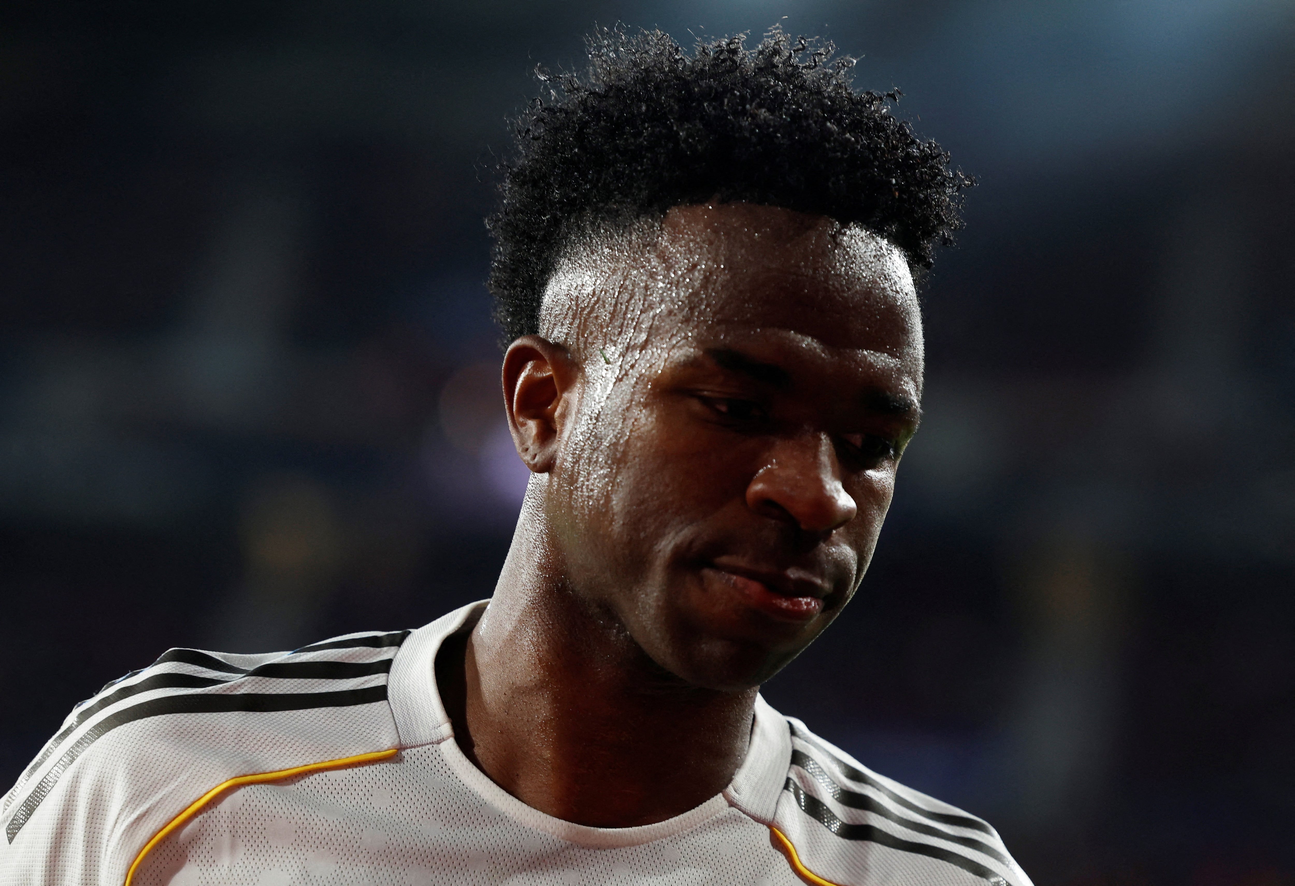 Vini Jr. olha para baixo no campo com cara fechada