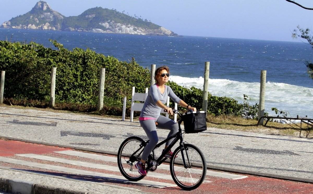 Adriana Esteves e Vladimir Britcha andam de bicicleta na praia da Barra, no Rio