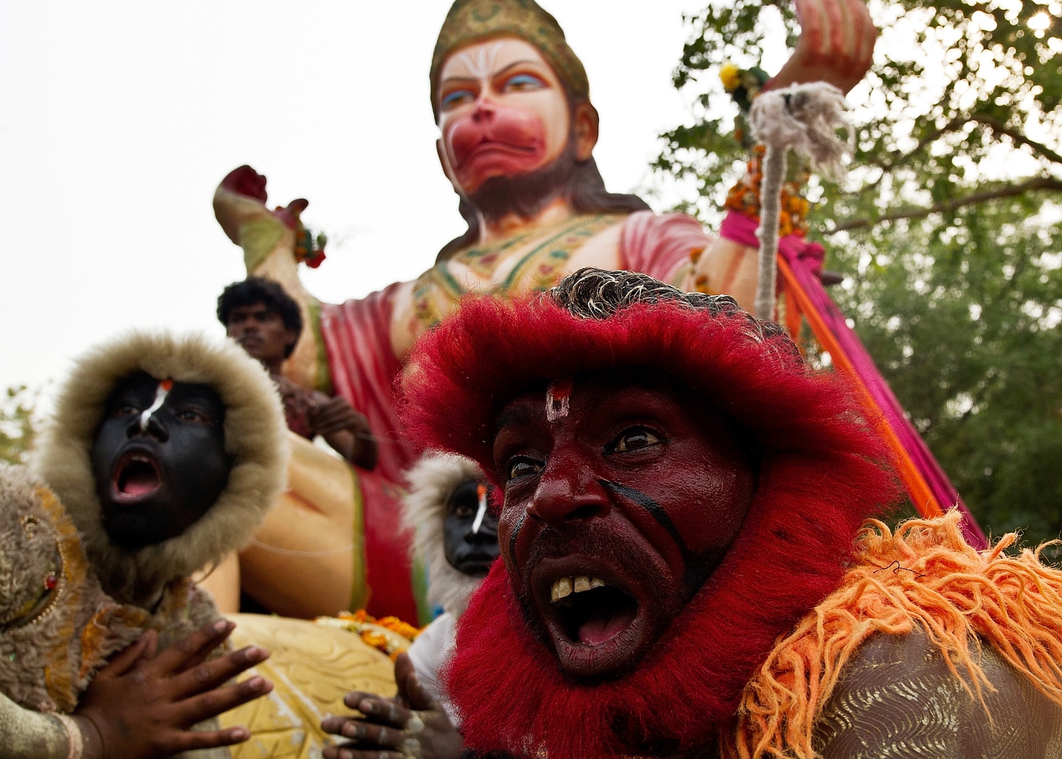 Além de se fantasiarem como macacos, os homens também imitam o animal enquanto circulam a imagem do deus Hanuman
