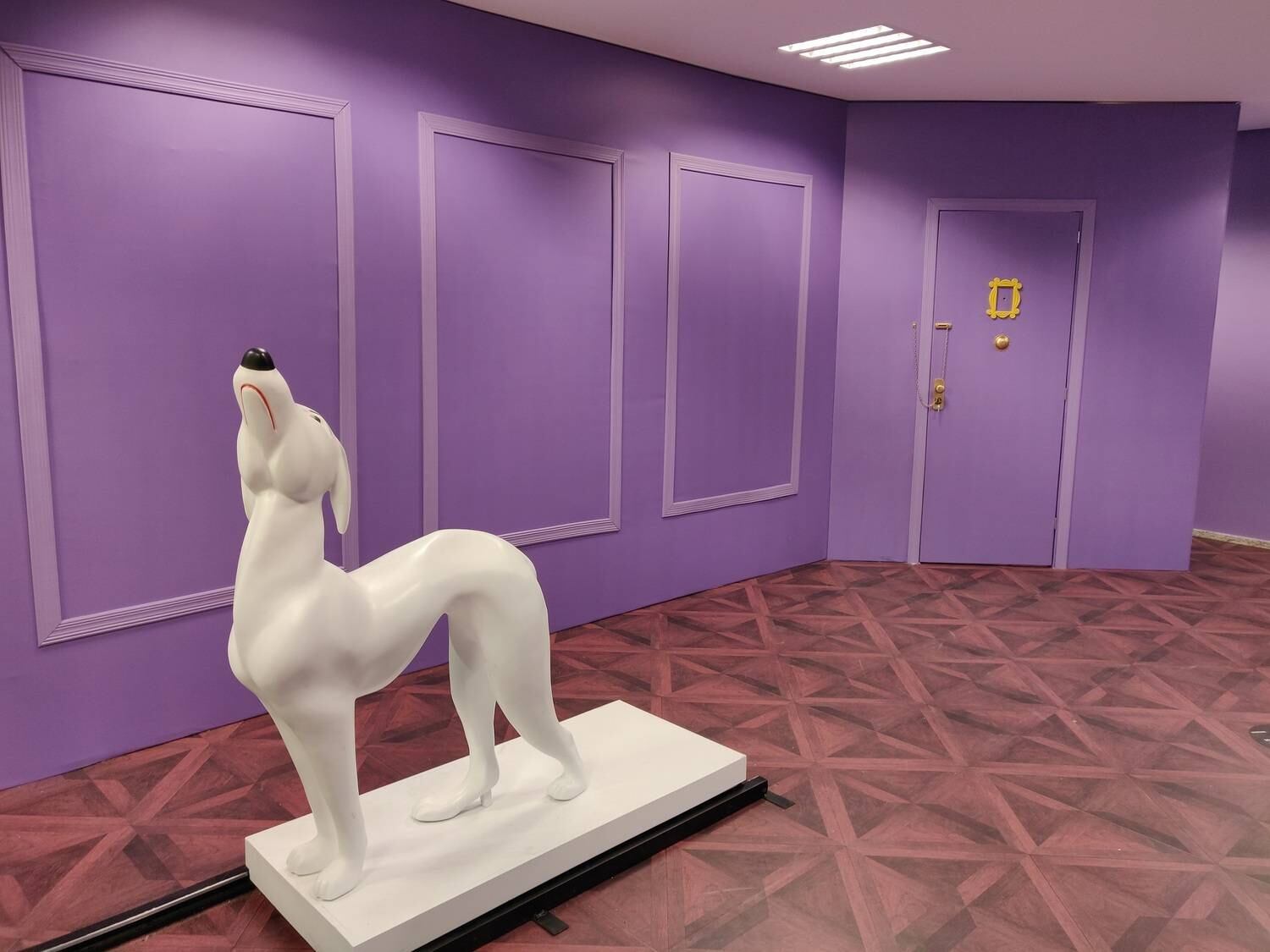 Falando em começo, que tal esse cenário com a porta roxa com moldura amarela, além da estátua do cachorro com a cabeça erguida de Joey para você deslizar