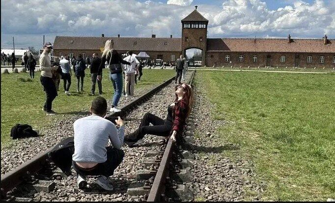Turista faz pose desrespeitosa em frente ao antigo campo de concentração de Auschwitz