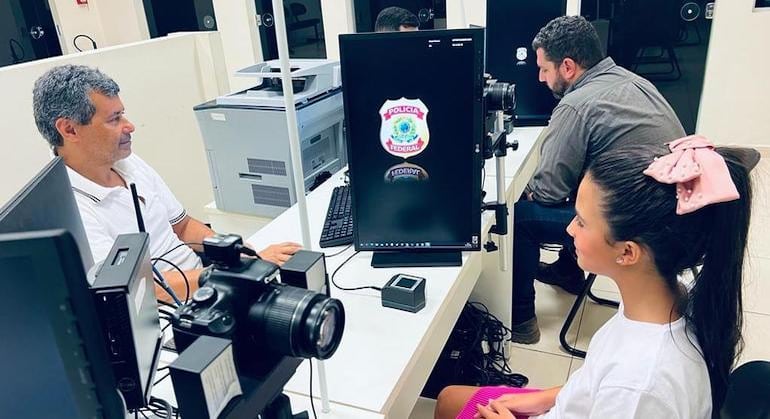 Wilson Quirino, auxiliar administrativo da Polícia Federal, e Elleonora Pagnanelli, 10 anos, renovando o seu quarto passaporte, no posto da PF, em Ribeirão Preto, SP