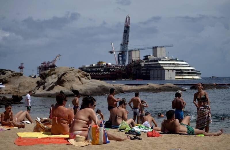 Pessoas tomam sol em
praia da ilha do Giglio, na Itália, enquanto o navio do cruzeiro Costa
Concordia continua encalhado no mar defronte