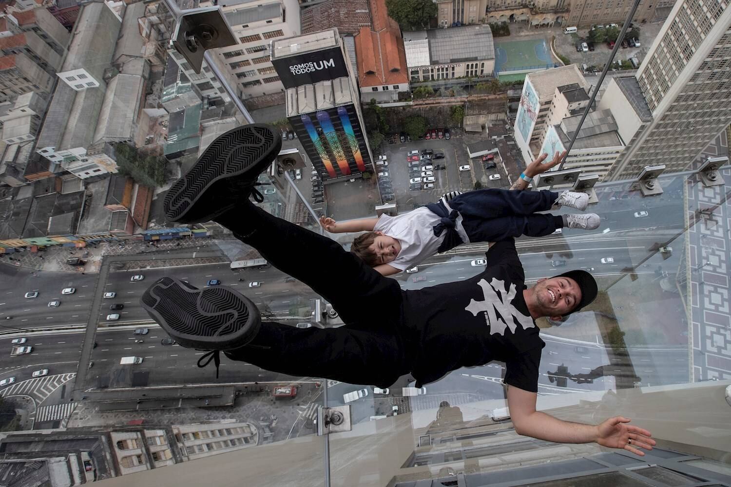AME7991. SAO PAULO (BRASIL), 11/08/2021.- Oscar Bueno y su hijo Thomas de 4 años se acuestan sobre el piso de vidrio del mirador Sampa Sky hoy, en Sao Paulo (Brasil). El mirador, inaugurado este domingo, está ubicado en una estructura de vidrio a 150 metros de altura en el piso 42 de Mirante do Vale, el edificio más alto de la ciudad de Sao Paulo en Brasil. EFE/ Sebastiao Moreira