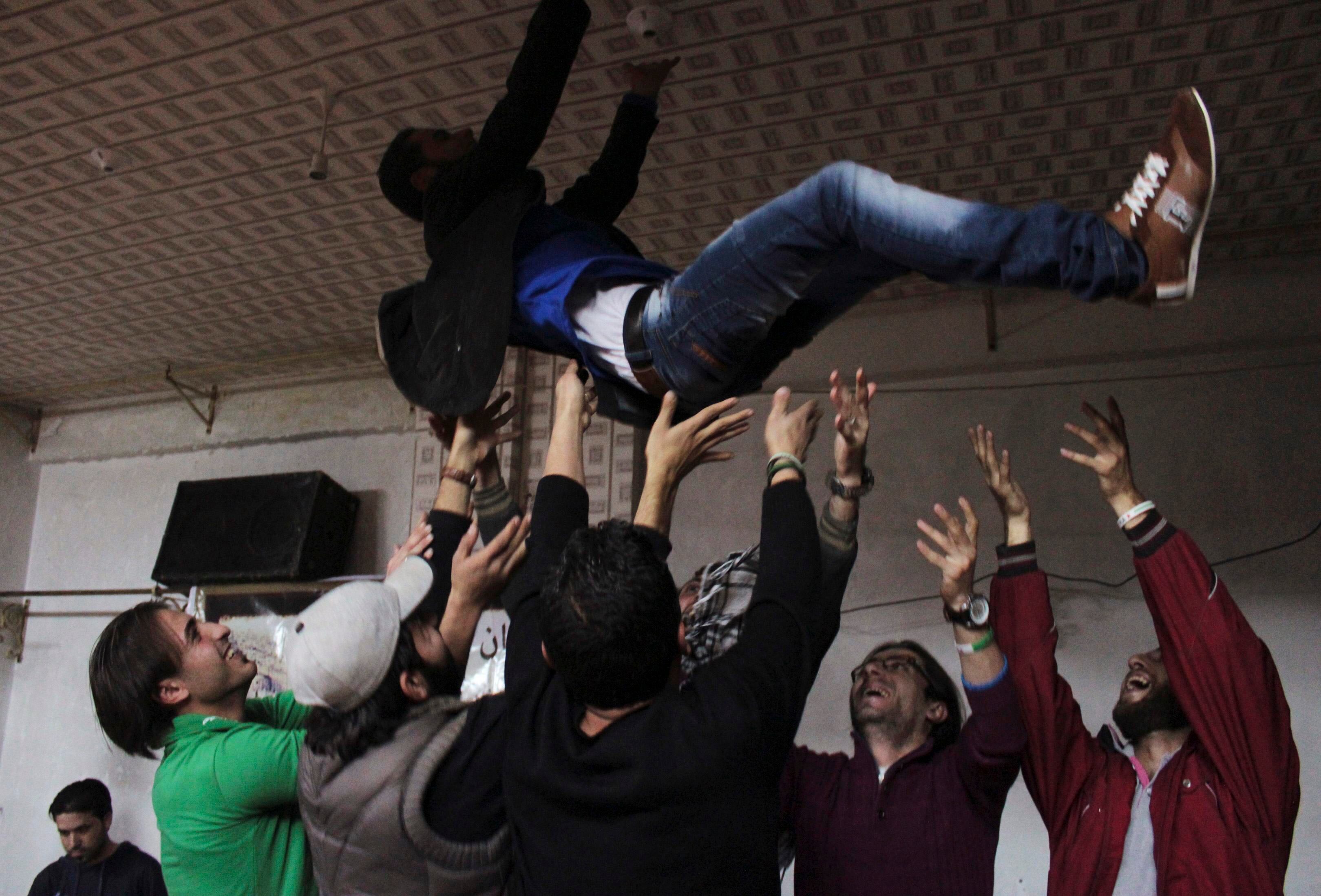 Rebeldes do Exército Sírio Livre festejam jogando um membro do grupo no ar durante celebração de casamento no bairro de Salaheddine, em Aleppo