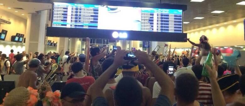 Foliões do Boi Tolo e passageiros fotografaram o cortejo diante do painel de voos do aeroporto