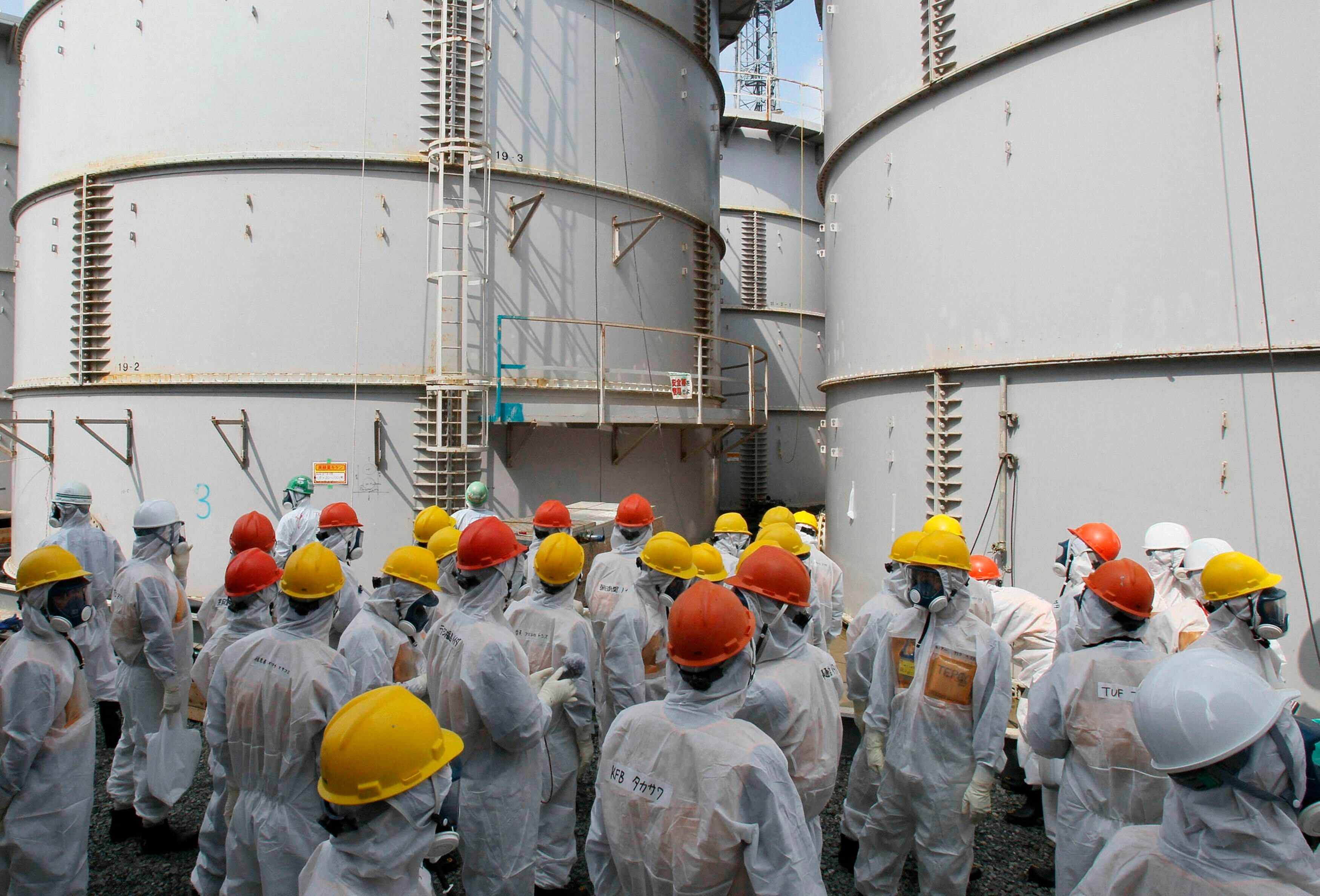 Inspetores observam um tanque com água contaminada na usina nuclear de Fukushima. Cerca de 1.100 toneladas de água "pouco radioativa" foram lançadas ao mar