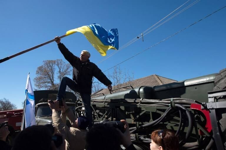 Manifestante pró-Rússia retira bandeira da Ucrânia de base aérea na cidade de Novofiodorovk
