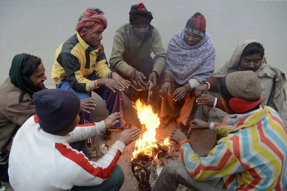 Mecânicos
indianos tentam se aquecer em estrada de Amritsar