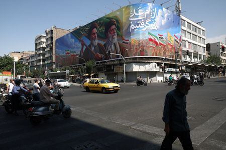Pessoas passam por um outdoor representando o falecido líder da Revolução Islâmica, aiatolá Ruhollah Khomeini, e o falecido líder supremo do Irã, aiatolá Ali Khamenei, em uma rua de Teerã, Irã