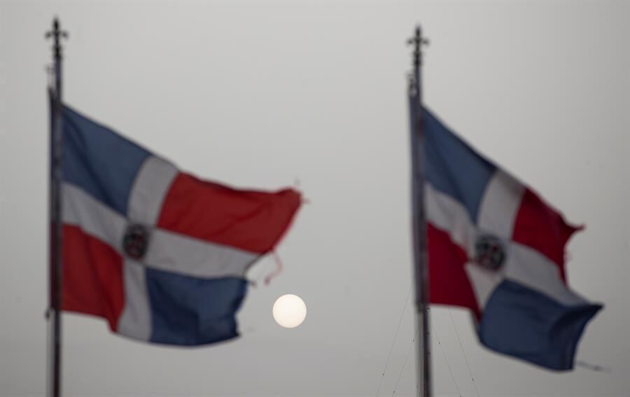 Bandeiras da República Dominicana em Santo Domingo com sol coberto pela nuvem de poeira do Saara
