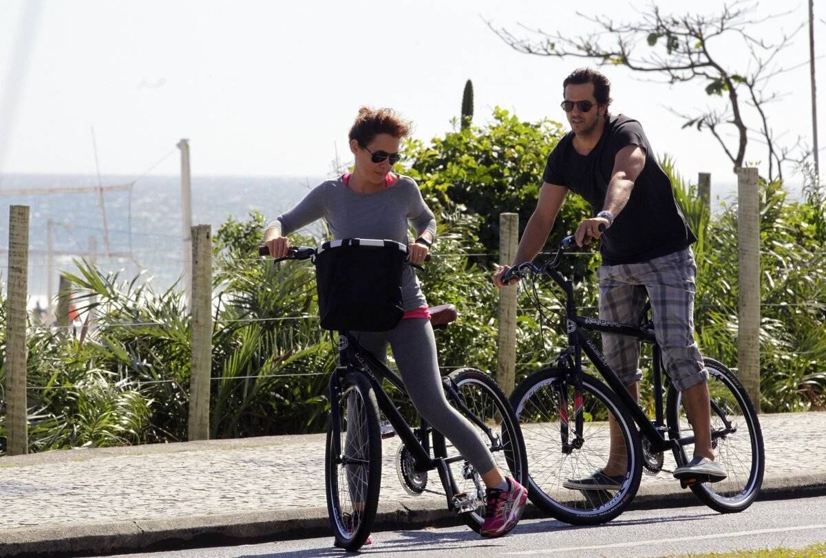 Adriana Esteves e Vladimir Britcha andam de bicicleta na praia da Barra, no Rio