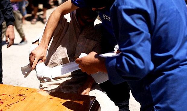 Após o ataque, um homem que assistia à punição pública enfaixa o que restou do braço da vítima