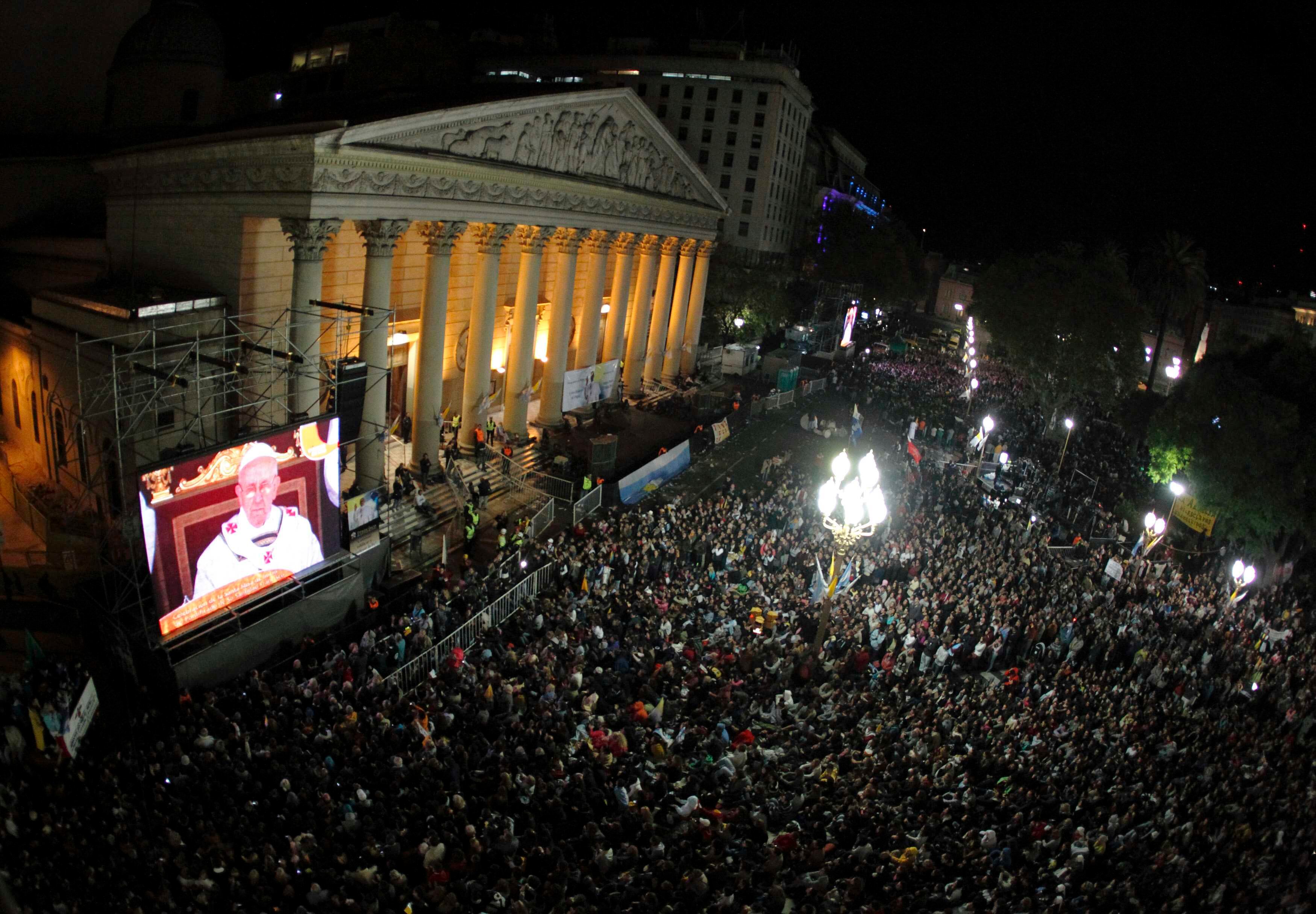 Fiéis assistem à missa inaugural de papa Francisco em uma tela gigante ao lado da Catedral Metropolitana, em Buenos Aires