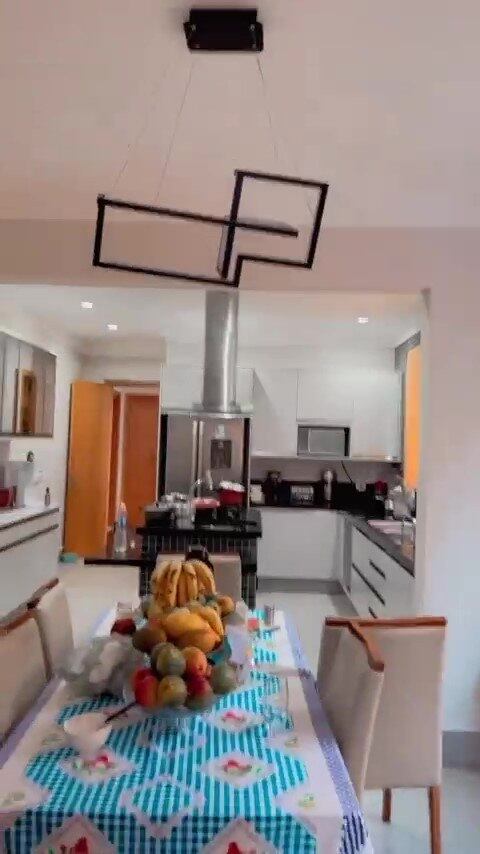 A cozinha tem uma ilha, geladeira de duas portas, armário espelhado e é toda trabalhada no contraste entre branco e preto
