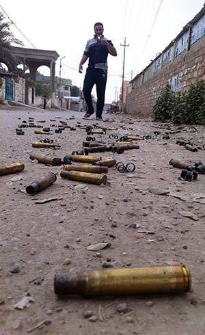 Homem tira fotos de cartuchos de balas usadas durante combates em Ramadi