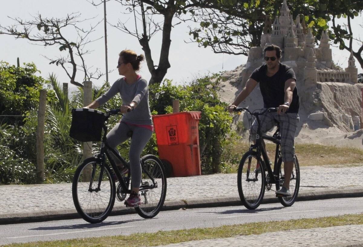 Adriana Esteves e Vladimir Britcha andam de bicicleta na praia da Barra, no Rio