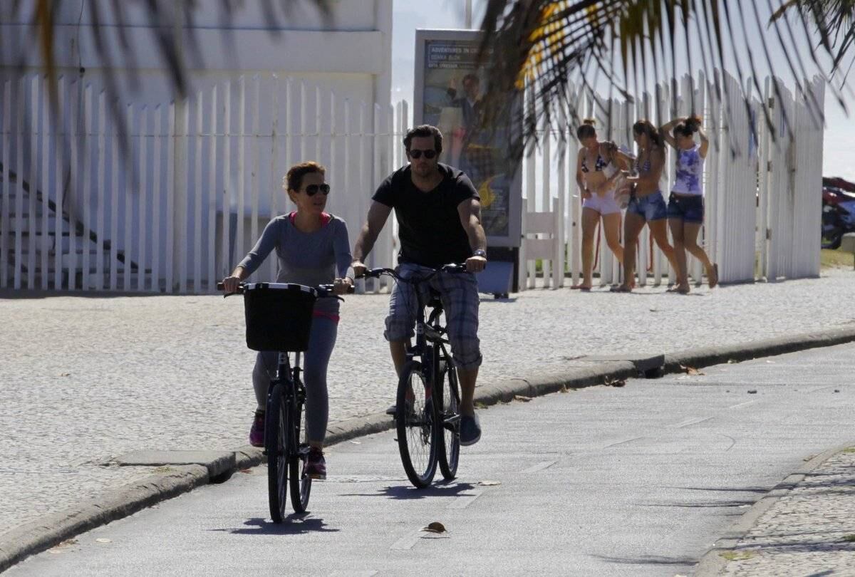 Adriana Esteves e Vladimir Britcha andam de bicicleta na praia da Barra, no Rio