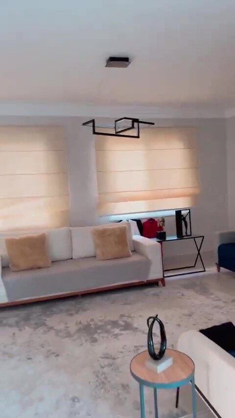 Ao subir a escada, há acesso para outra sala, com decoração básica e minimalista - além de mais um lustre moderno