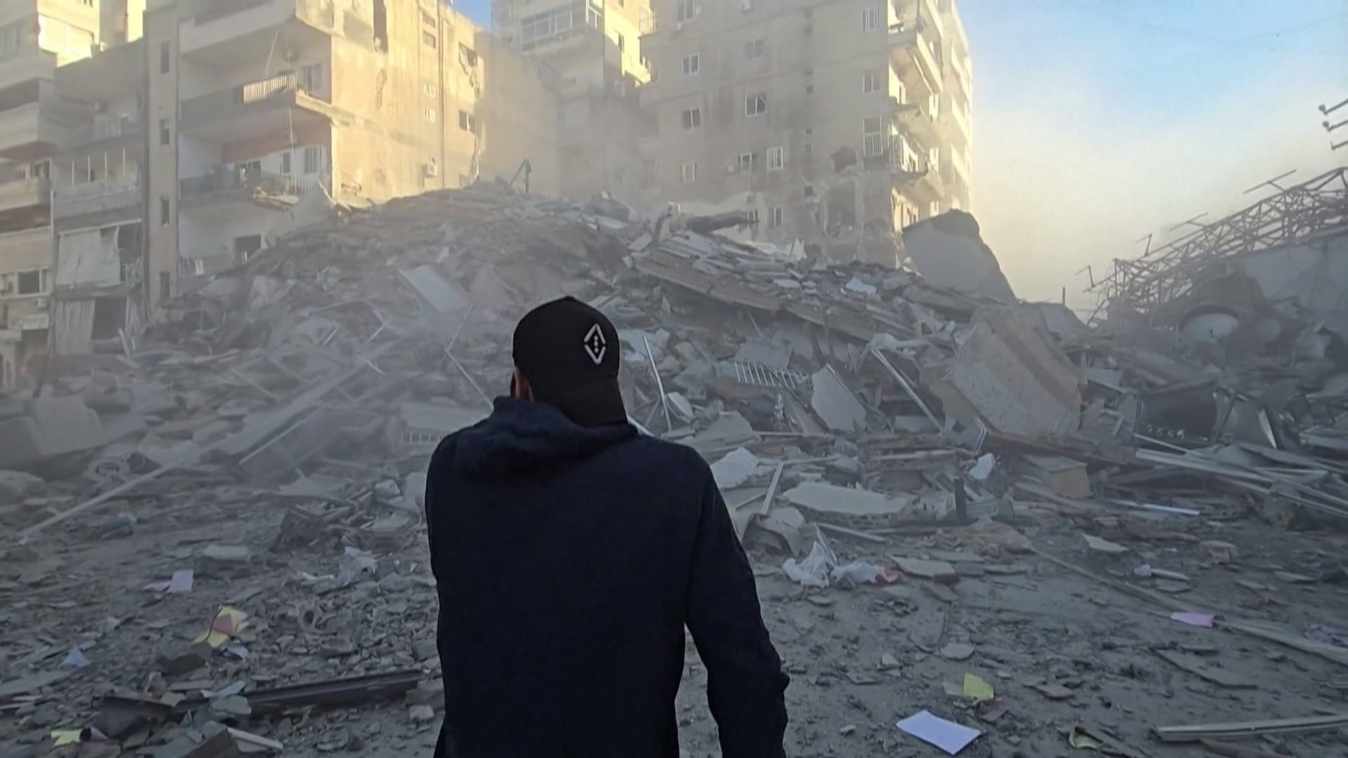 Homem de costas em meio a escombros