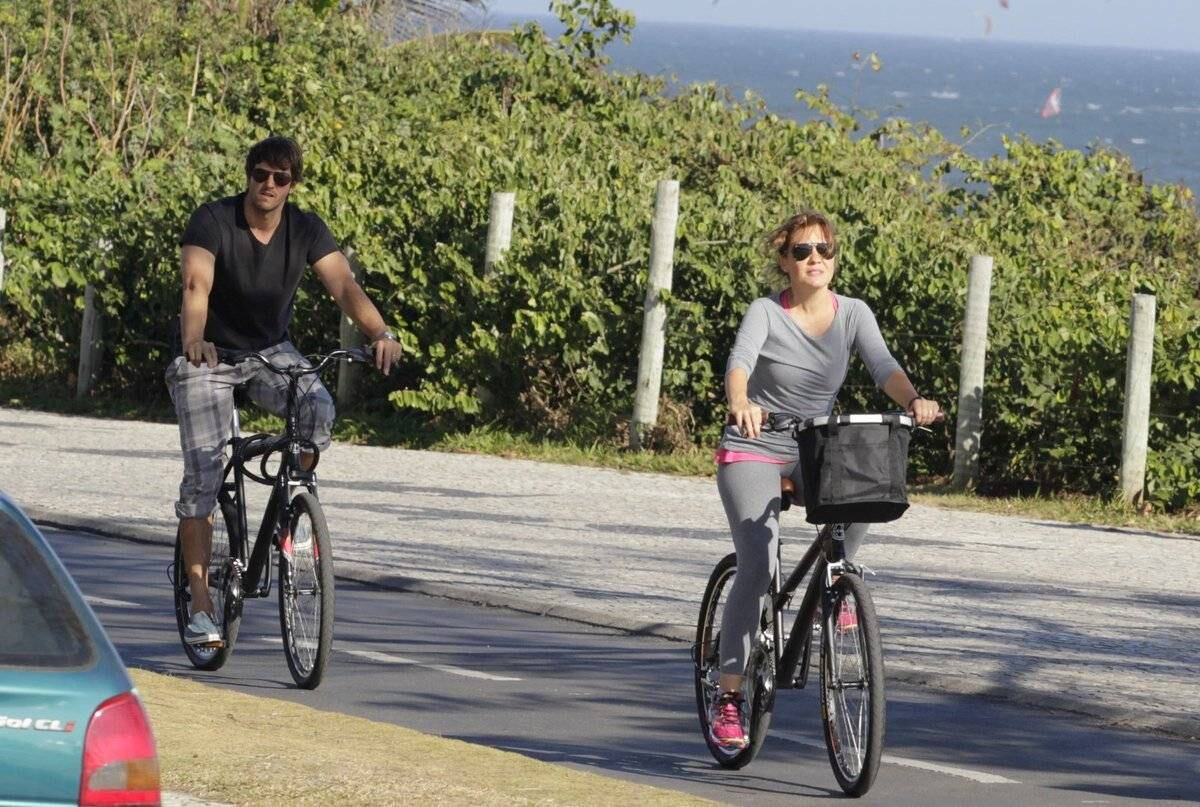 Adriana Esteves e Vladimir Britcha andam de bicicleta na praia da Barra, no Rio