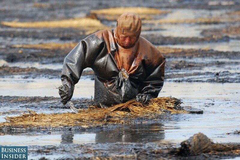 Trabalhador tenta retirar o petróleo das águas do porto Dalian em julho de 2010


