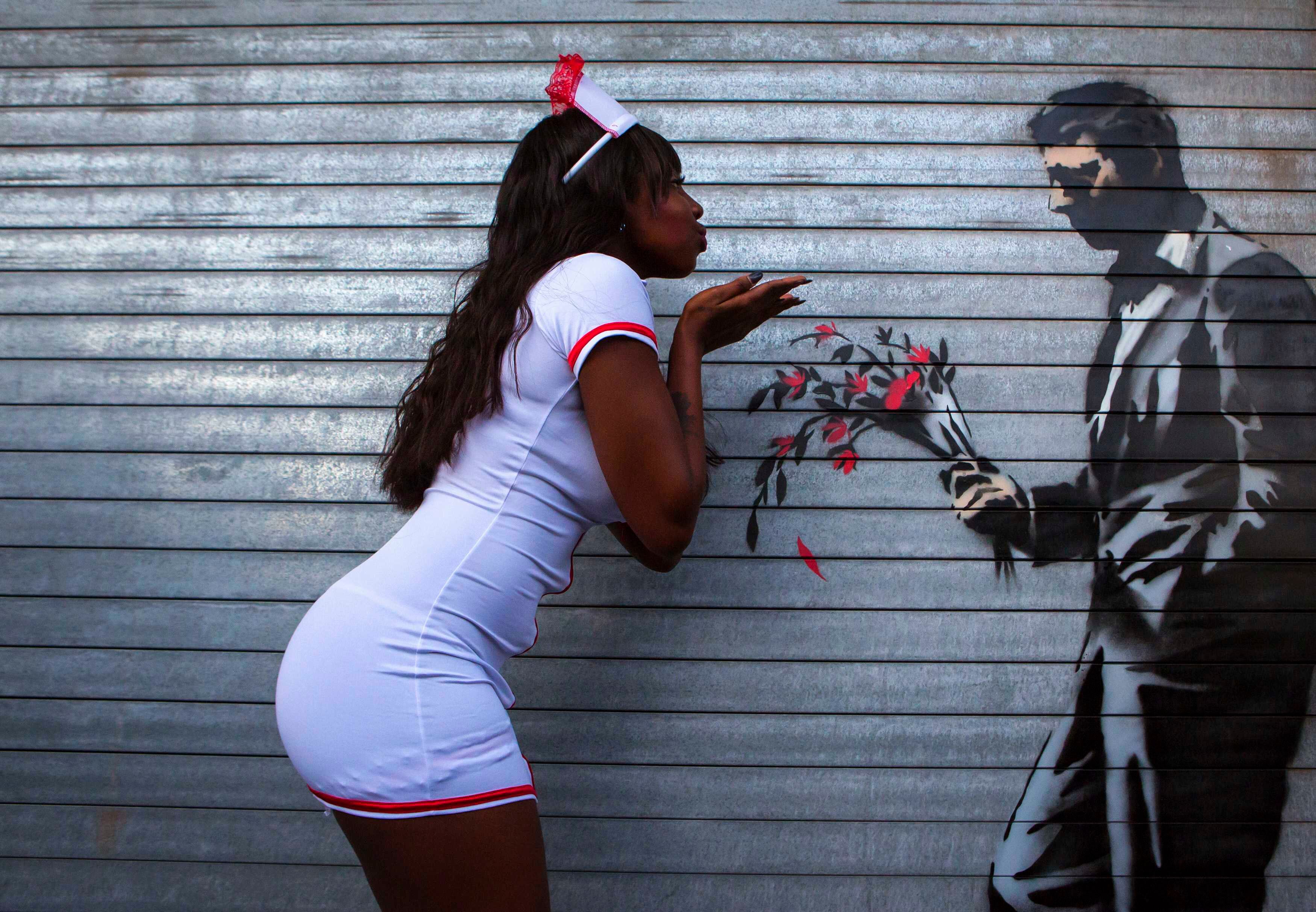 Dançarina posa ao lado de uma instalação em grafite, pintada pelo artista britânico Banksy na porta da frente do Clube Hustler, em Nova York, Estados Unidos