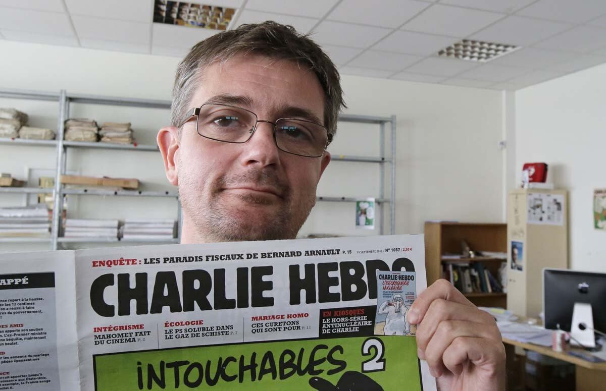 O diretor de publicação do Charlie Hebdo, Charb, mostra a primeira página de seus jornal para fotógrafos em Paris, em 2012. O semanário de humor já foi alvo de ataques no passado por conta de suas sátiras relacionadas ao profeta Maomé