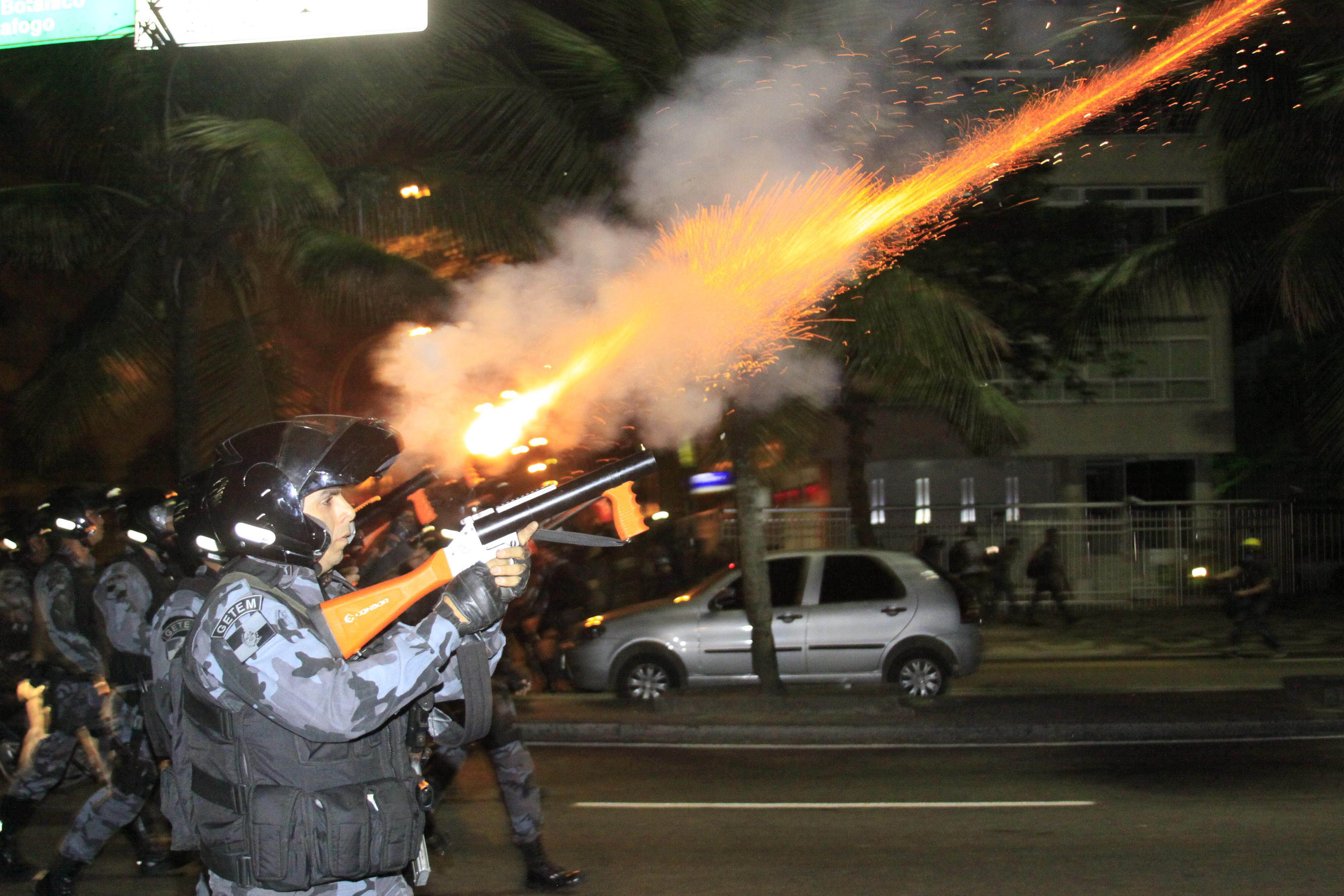 Policial do Batalhão de Choque dispara tiro de bala de borracha para dispersar a multidão que tentava furar o bloqueio próximo ao prédio onde mora o governador