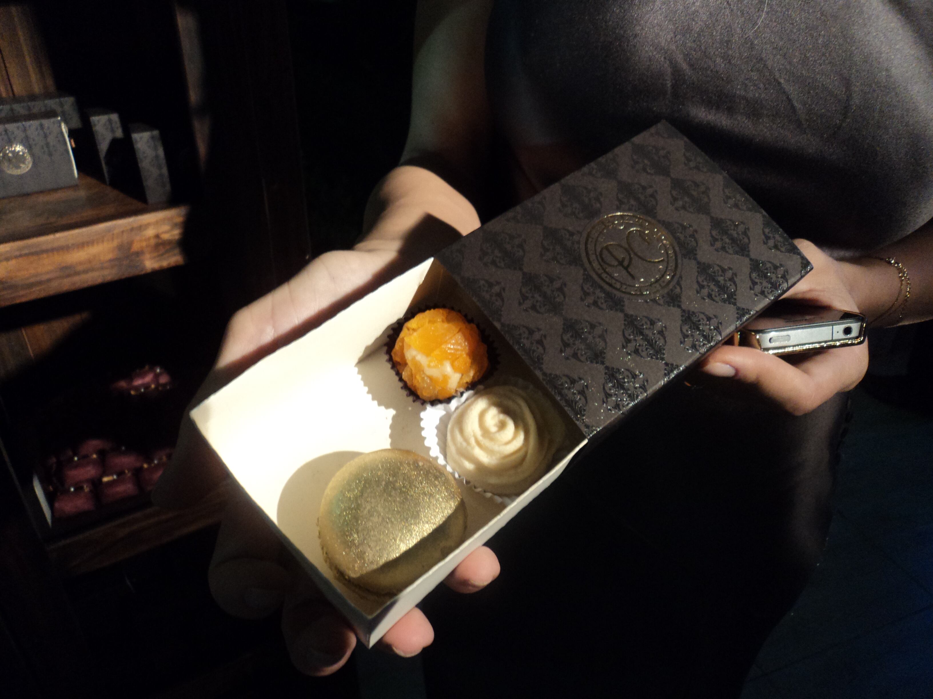 Como lembrancinha foi oferecida aos convidados uma caixinha com doces finos e macarons com o monograma do casal