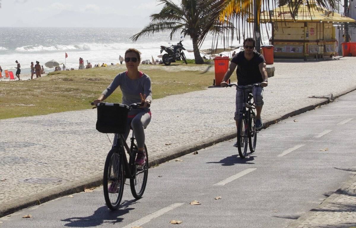 Adriana Esteves e Vladimir Britcha andam de bicicleta na praia da Barra, no Rio
