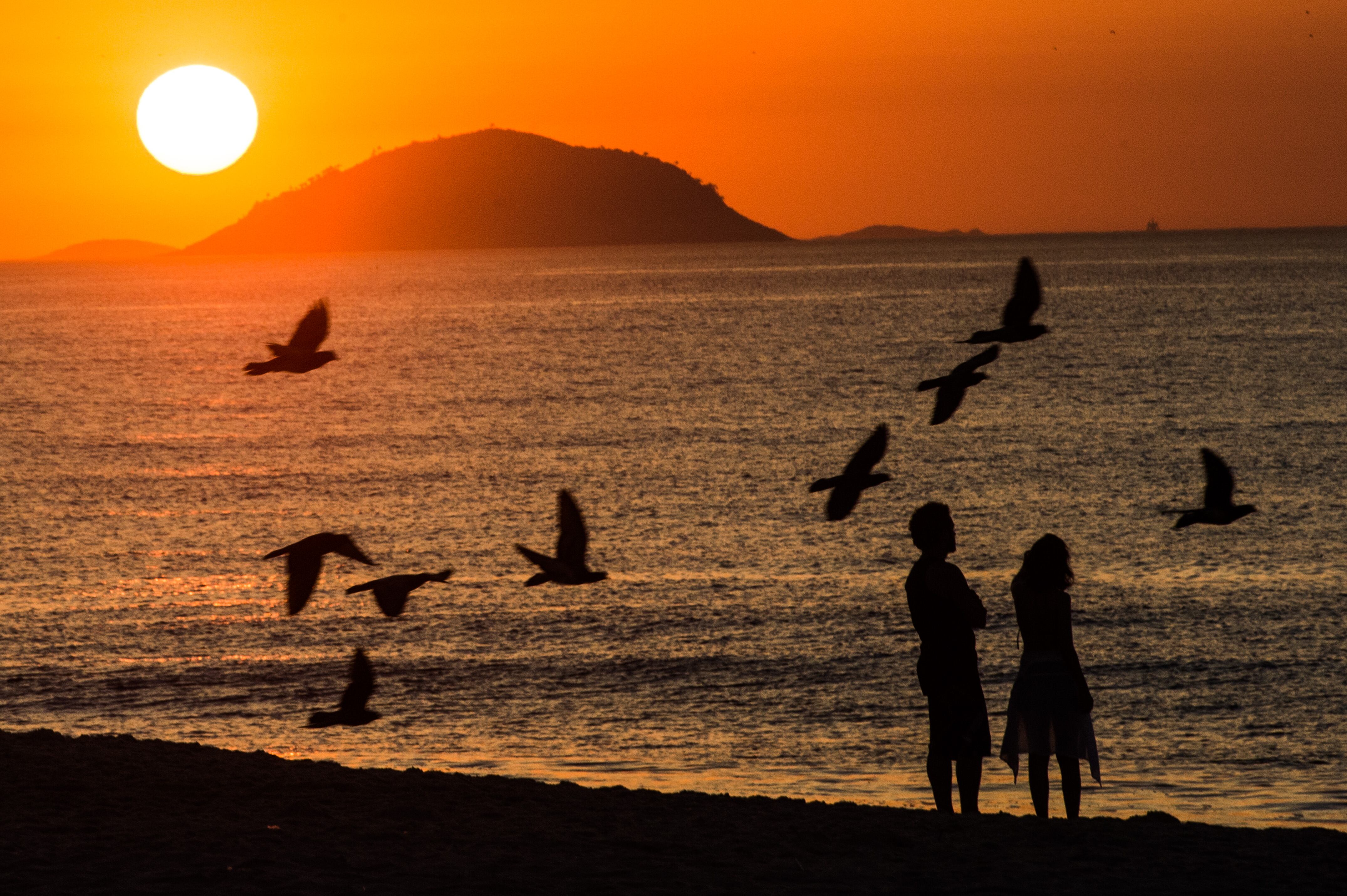 Casal observa o nascer do sol na praia de Copacabana, no Rio de Janeiro
