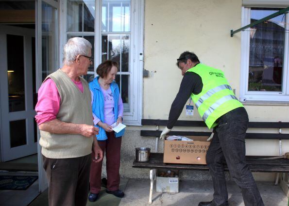 Um voluntário de proteção civil levou a comida a um casal de idosos devido ao medo da doença por coronavírus. Medvode, Eslovênia
