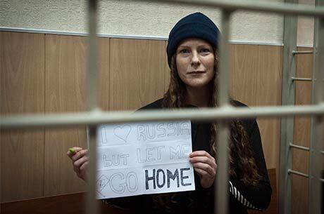 Brasileira Ana Paula Maciel segura cartaz durante audiência na corte de Murmansk, Rússia: “Eu amo a Rússia, mas me deixem ir para casa”