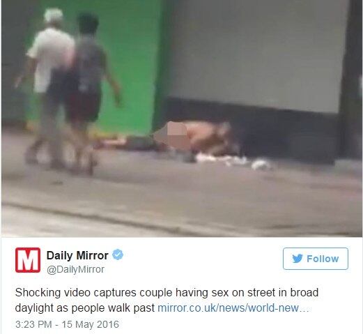 O homem abaixa as calças até a altura pouco abaixo dos joelho, enquanto a mulher se apoia de costas sobre alguns trapos brancos 