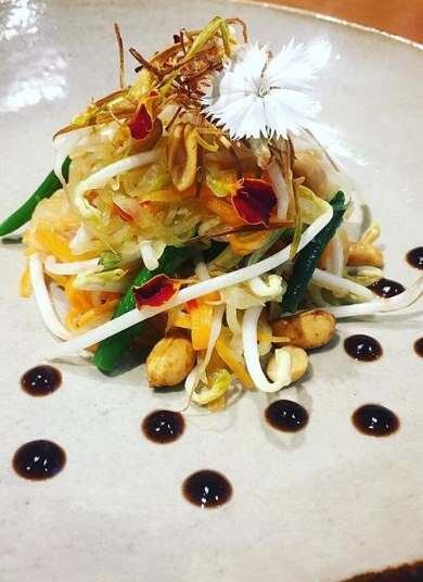 Som Tam com Tonkatsu e Camarões 
Por Maíra Knox 

Ingredientes (para o preparo da salada):
1 mamão verde
50g de Moyashi ( broto de feijão)
½ cenoura 
2 pimentas frescas
3 dentes de alho
3 lâminas de gengibre
2 colheres (sopa) de suco de limão
1 colher (sopa) de açúcar de palma (use açúcar mascavo, caso não encontre)
5 ou 6 vagens
2 tomates (ou de 10 a 12 tomates cerejas)
1/3  xícara de amendoim picado
2 colheres sopa de "nam pla" 
1/4 colher chá de sal
8 Camarões grandes
Flores comestíveis ou brotos

Ingredientes (Molho tonkatsu fácil):
2 colheres (sopa) de worcestershire
2 colheres (sopa) de ketchup
1 colher (sopa) de molho de ostras
1 colher (café) de açúcar 

Misture todos os ingredientes e reserve.

Preparo da salada:

Lave o mamão descascado e cortado ao meio em água corrente, e descarte todas as sementes. Depois, rale a fruta em tiras finas e compridas. Em seguida, rale a cenoura, pique o alho em pedaços bem pequenos e corte as vagens em pedaços médios (aproximadamente 3 cm). Então, corte os tomates em 4 ou 6 pedaços (se escolheu tomate cereja, corte-os ao meio). Em um pilão, coloque o alho e as pimentas e amasse até triturá-los. Depois, adicione o suco de limão, o açúcar, o "nam pla", o sal e misture até o açúcar derreter bem. Coloque a vagem e amasse de leve, sem triturá-las. Faça o mesmo com o tomate. Adicione o papaya, o moyashi e a cenoura, e misture bem. Adicione os amendoins e emprate. Para finalizar, decore com o molho tonkatsu e flores comestíveis.

