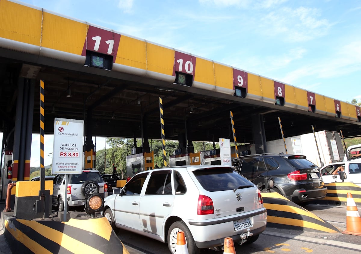 Praça de pedágio com carros parados que esperam para pagar tarifa em uma rodovia