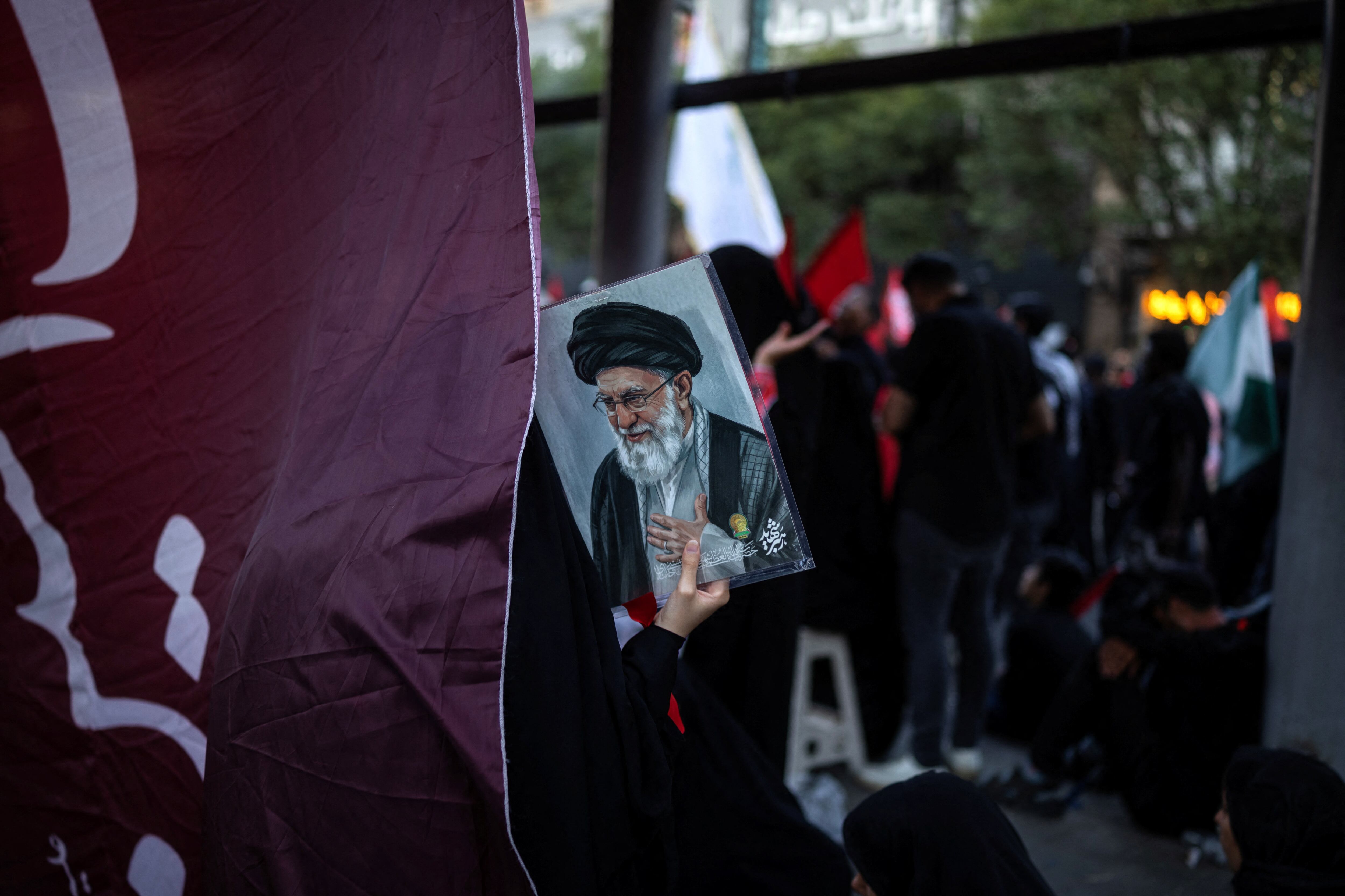 Um enlutado segura um retrato do falecido Líder Supremo do Irã, o Aiatolá Ali Khamenei, morto em 28 de fevereiro em ataques aéreos israelenses e americanos, durante um cortejo fúnebre no dia de seu sepultamento, em Mashhad, Irã