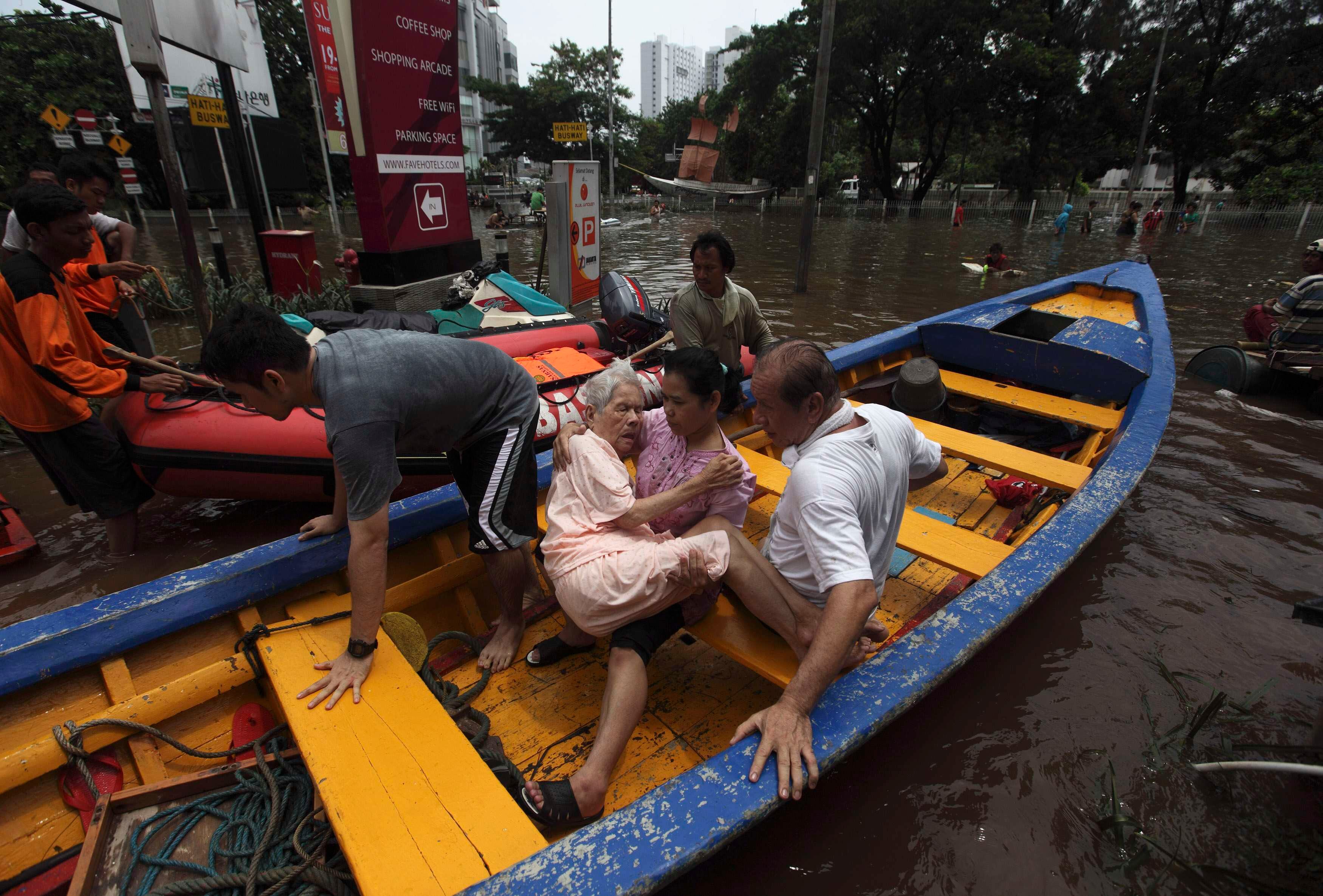 Vítimas da enchente em Jacarta, capital da Indonésia, são resgatadas de barco