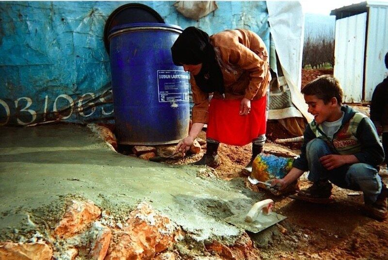 Mãe e filho constroem seu abrigo improvisado em um assentamento, no Vale do Bekaa. Eles foram fotografados por Mahmoud, de 10 anos