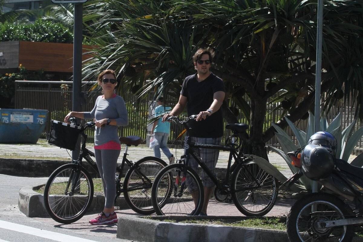 Adriana Esteves e Vladimir Britcha andam de bicicleta na praia da Barra, no Rio